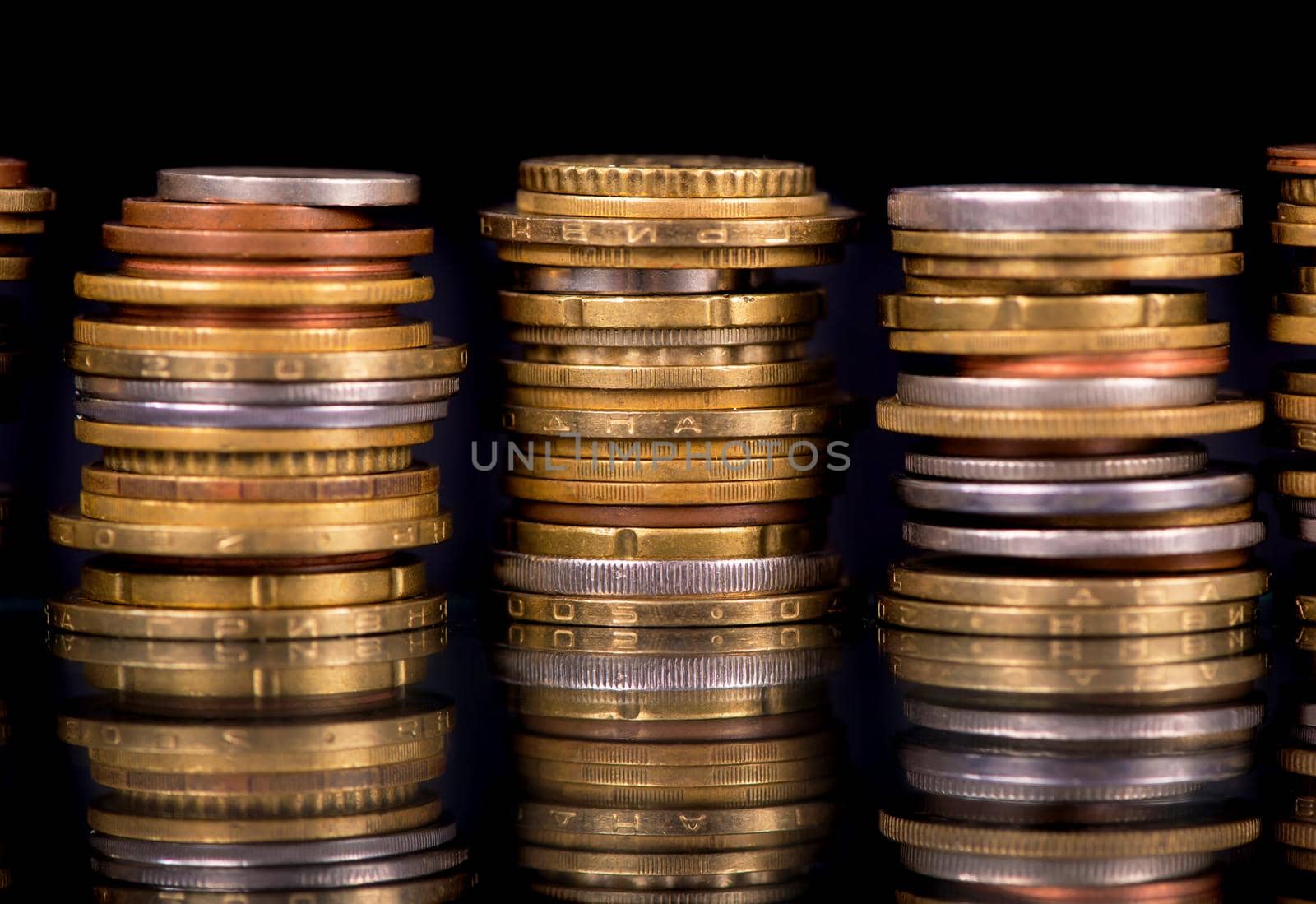 Stacks cf different country coins on black background.