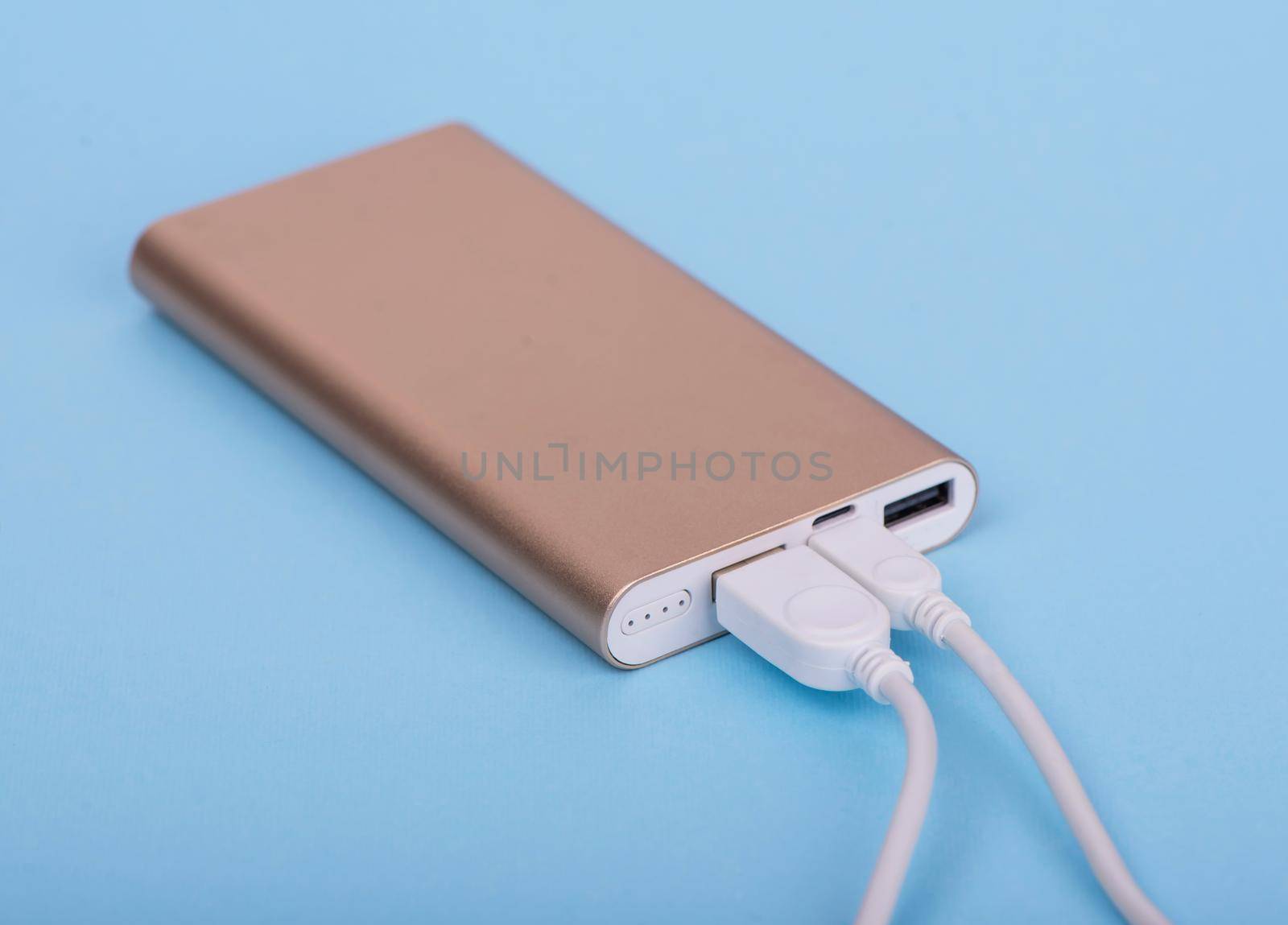 Smartphone charging with power bank on a blue background.