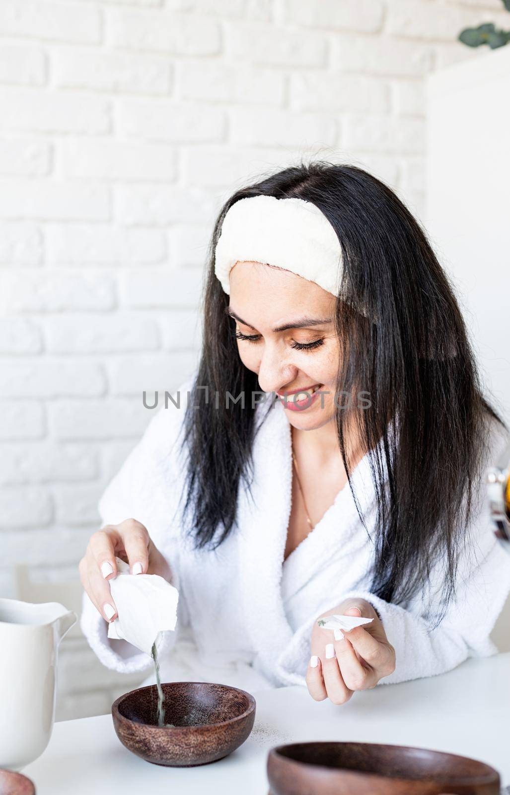 Spa and wellness concept. Self care. Happy smiling young woman in white bath towels making facial mask doing spa procedures