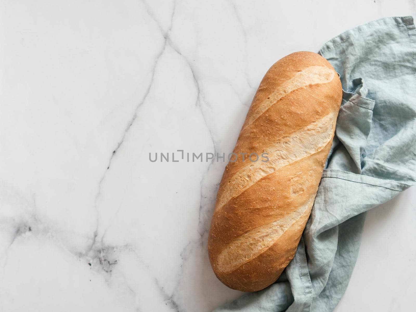British White Bloomer or European Baton loaf bread on white marble background. Top view or flat lay. Copy space for text or design.