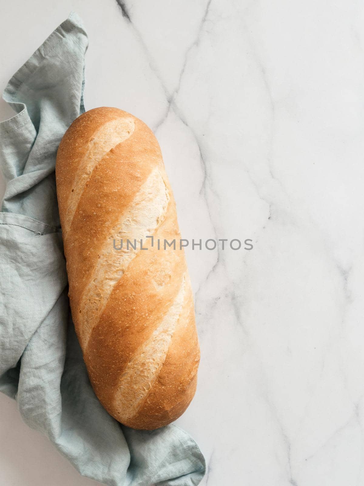 British White Bloomer or European Baton loaf bread on white marble background. Top view or flat lay. Copy space for text or design. Vertical.