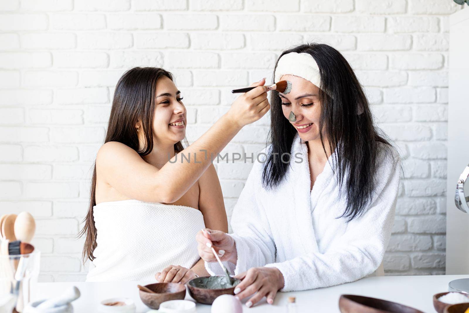 two beautiful women making facial mask having fun by Desperada