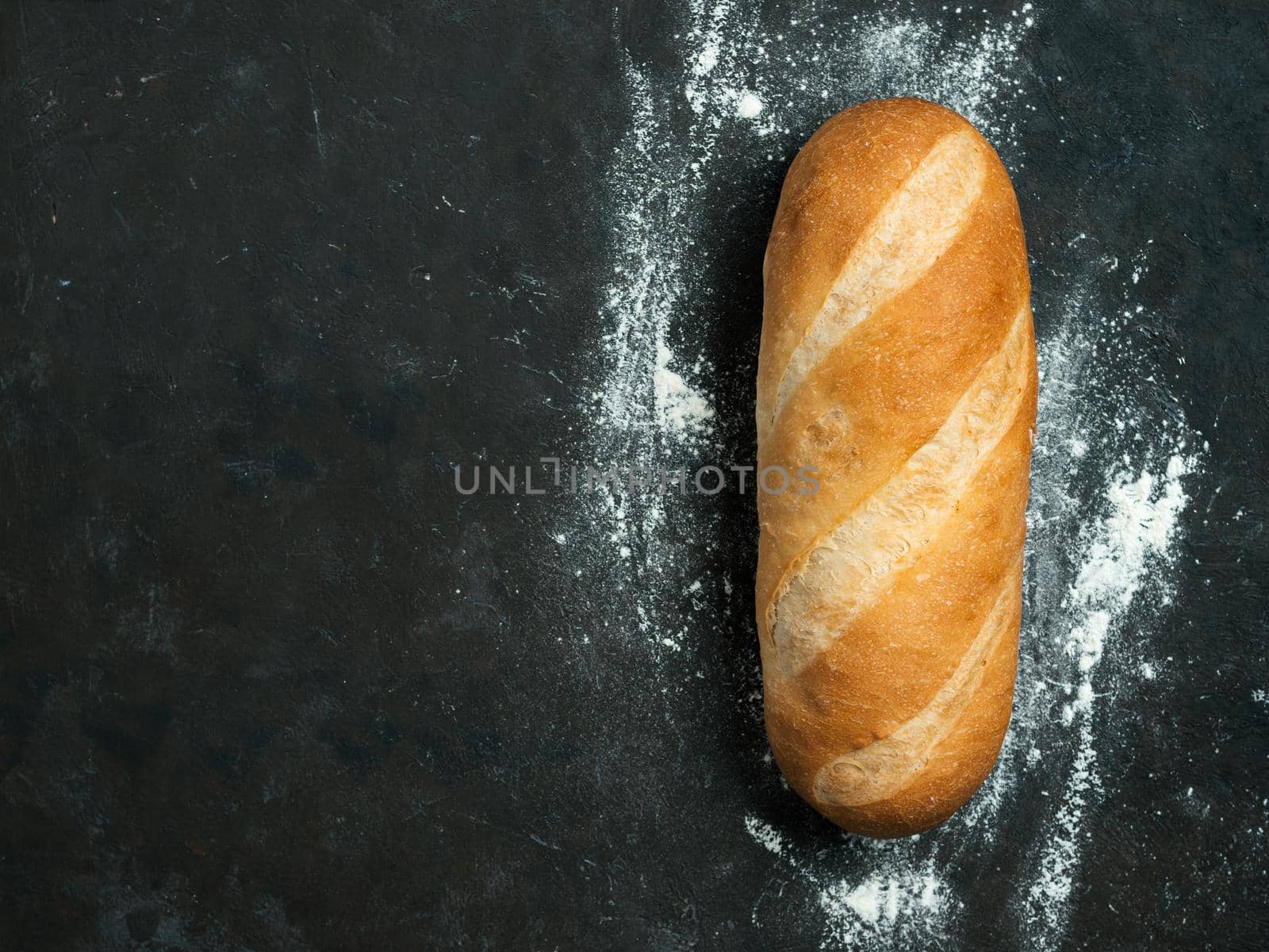 British White Bloomer or European Baton loaf bread on black background. Top view or flat lay. Copy space for text or design