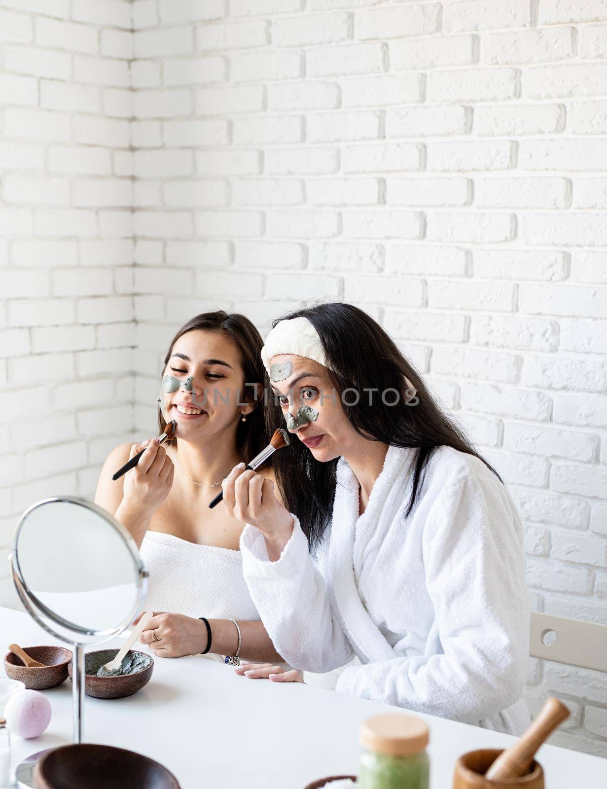 two beautiful women applying facial mask having fun by Desperada