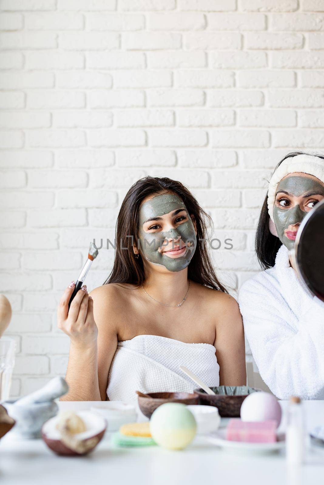 Spa and wellness concept. Self care. Portrait of a beautiful woman with long black hair applying facial mask doing spa procedures