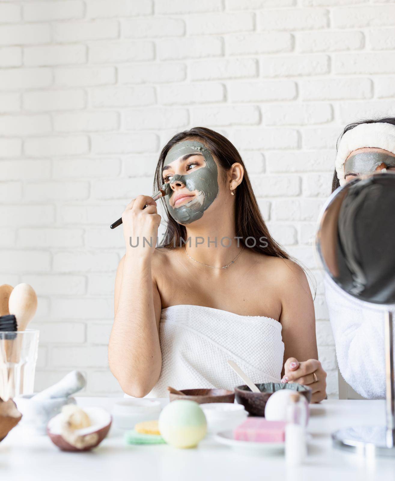 Spa and wellness concept. Self care. Portrait of a beautiful woman with long black hair applying facial mask doing spa procedures
