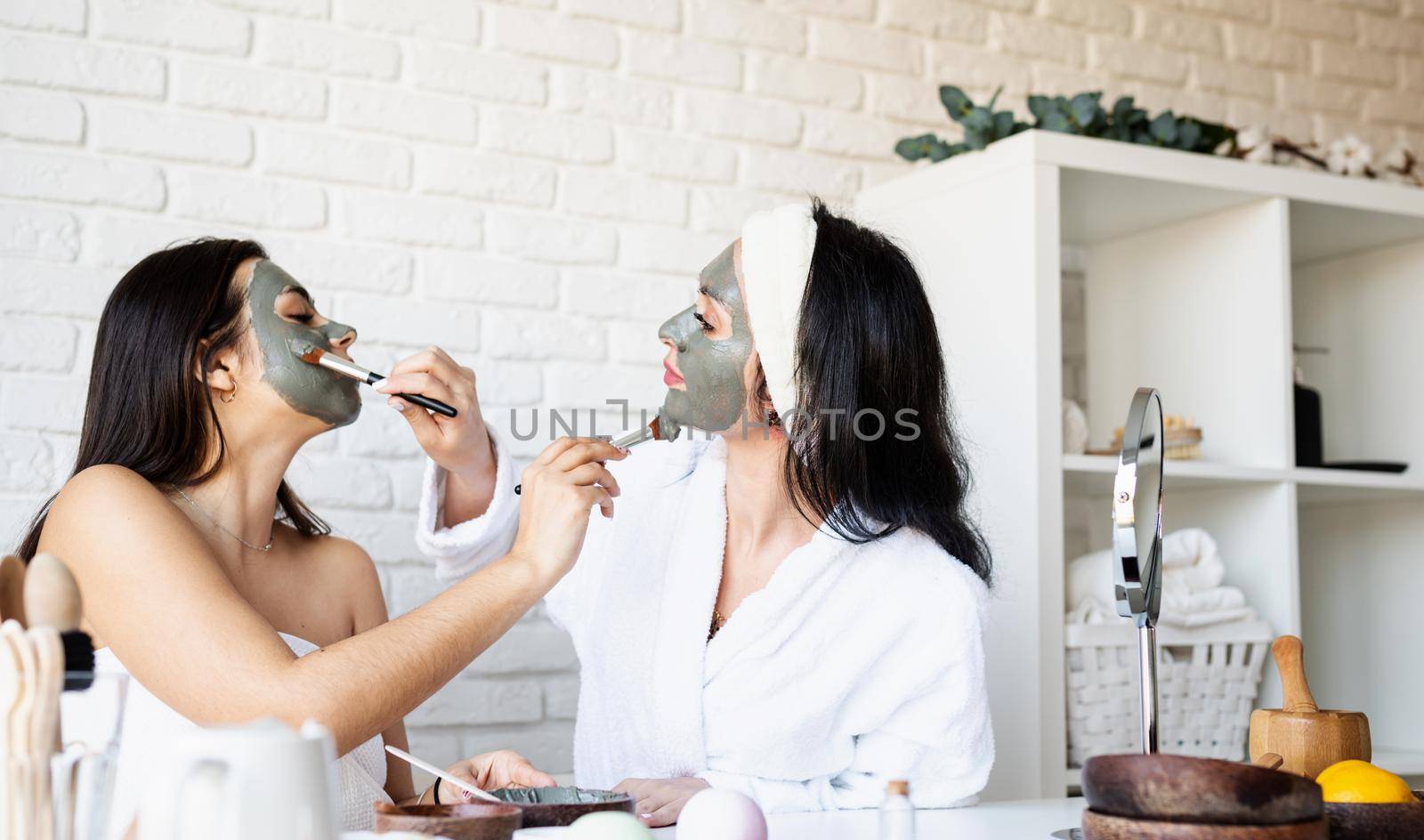 two beautiful women applying facial mask having fun by Desperada