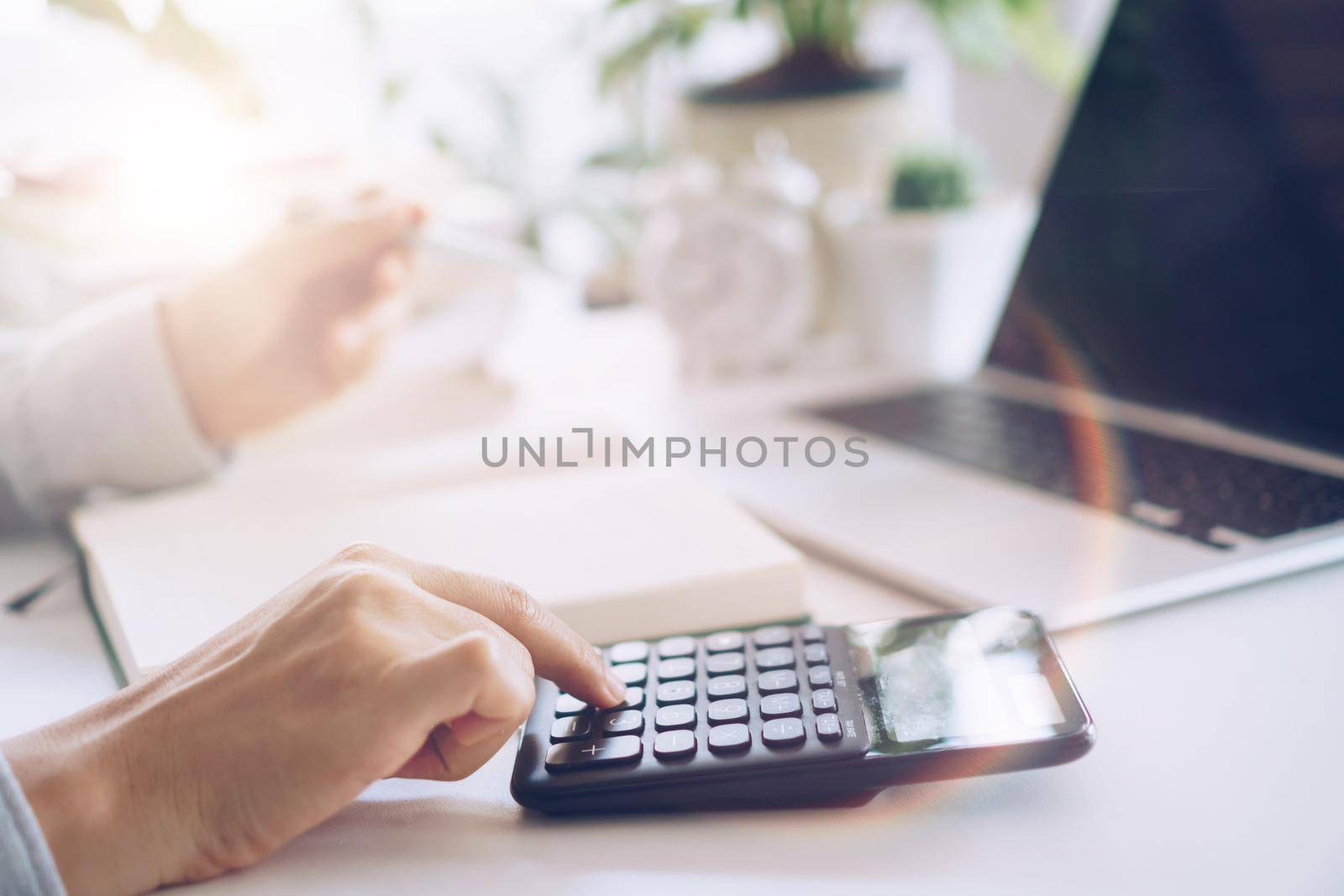 Woman is working on clean nature workspace at home with laptop, planner notebook and calculator. Business finance office. by Suwant