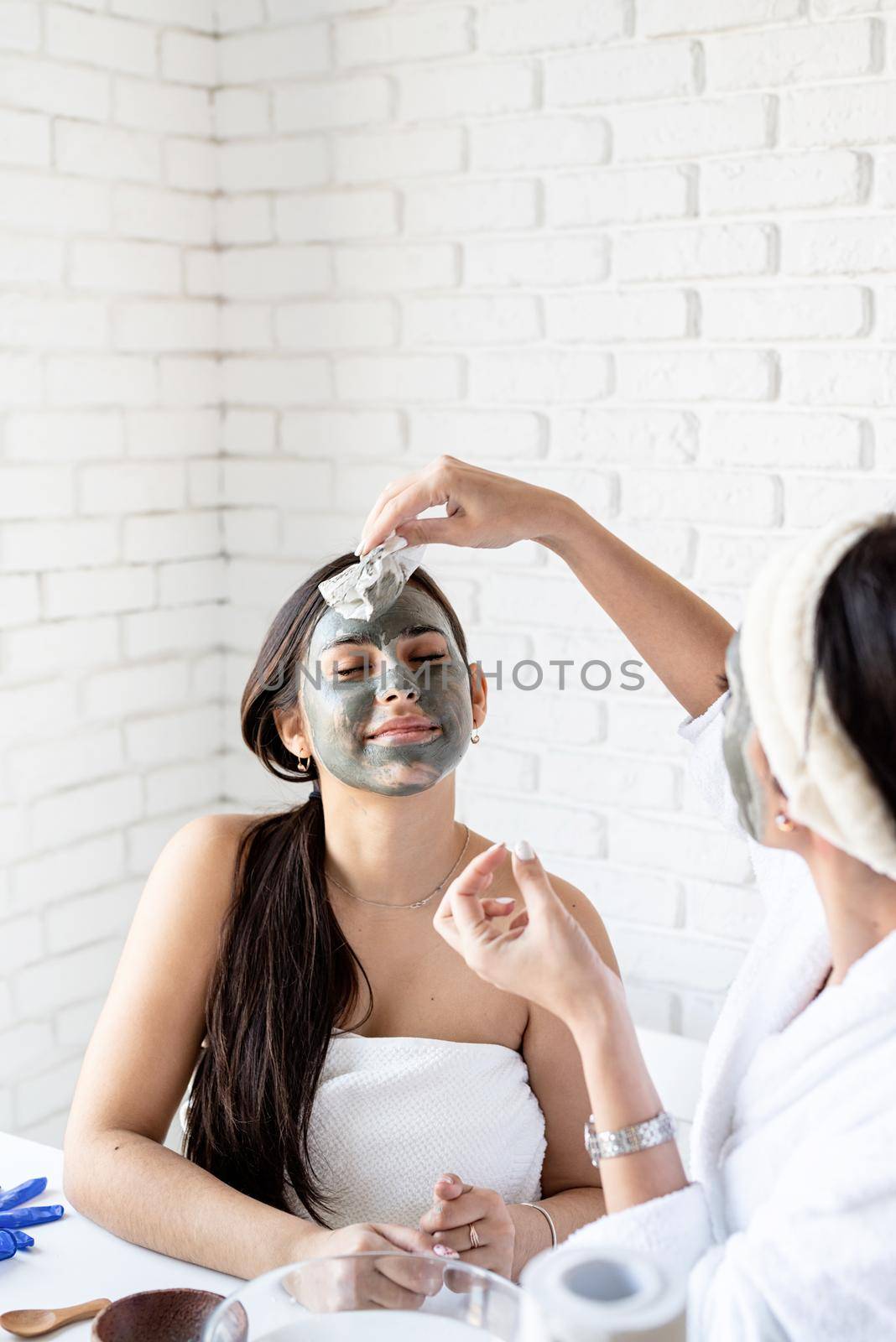 two beautiful women applying facial mask doing spa procedures by Desperada
