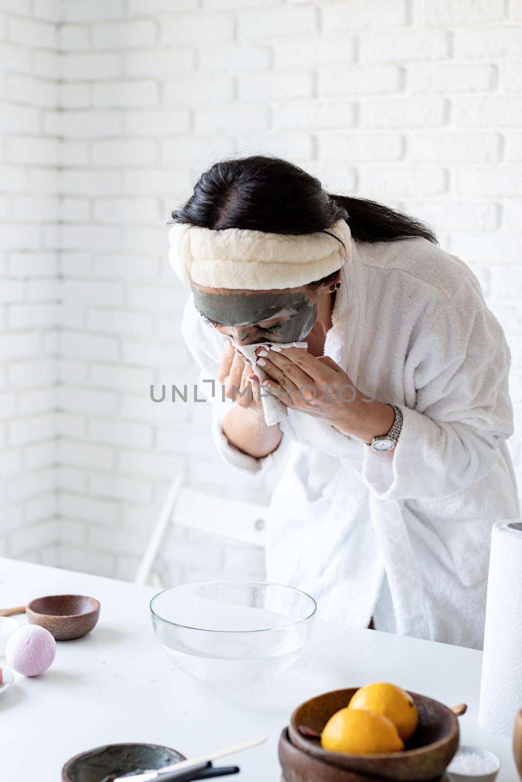 Spa and wellness concept. Self care. Portrait of a woman in white bath robes making facial mask doing spa procedures