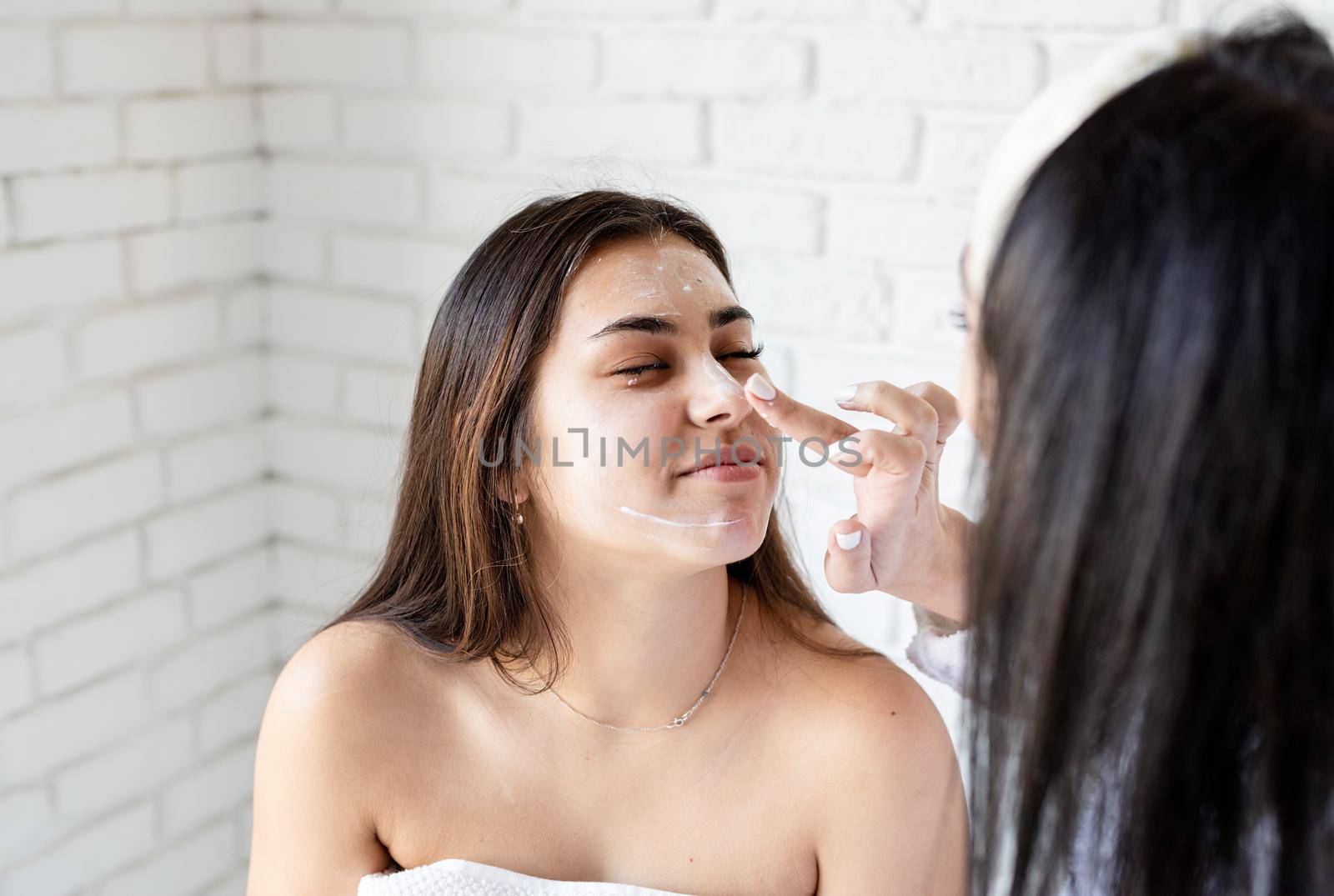 Spa and wellness concept. Self care. two beautiful women applying facial cream doing spa procedures