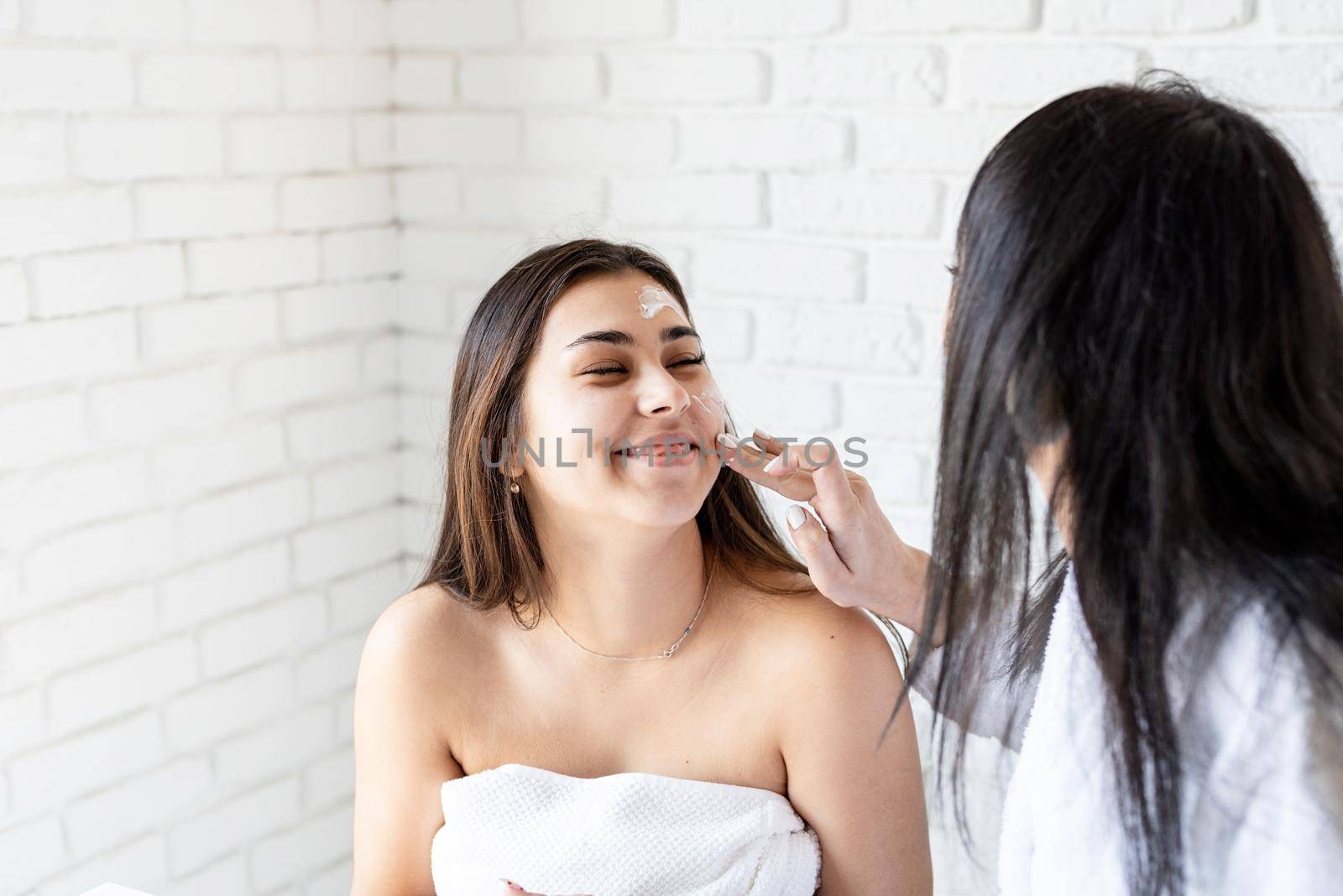 Spa and wellness concept. Self care. two beautiful women applying facial cream doing spa procedures