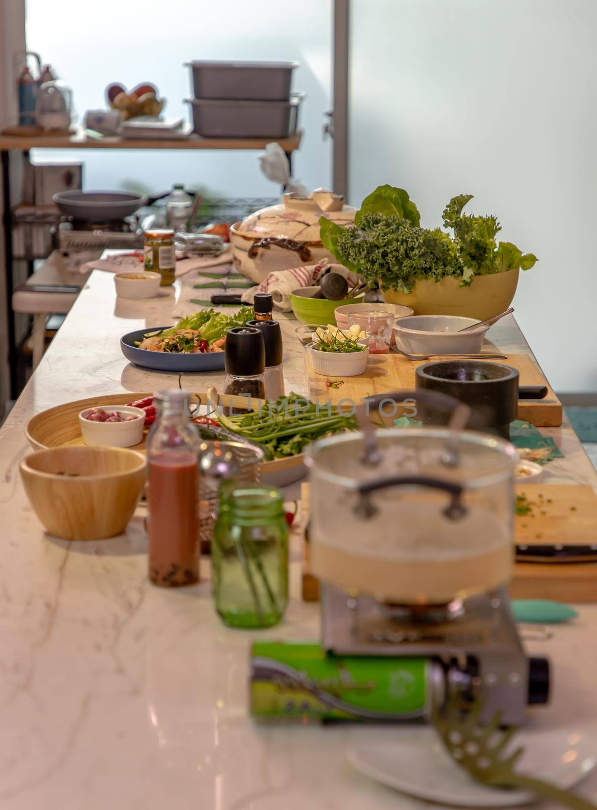 A kitchen with a cooking table in the middle of the room and the table is full of ingredients for cooking. The concept of a food healthy lifestyle. No focus, specifically.