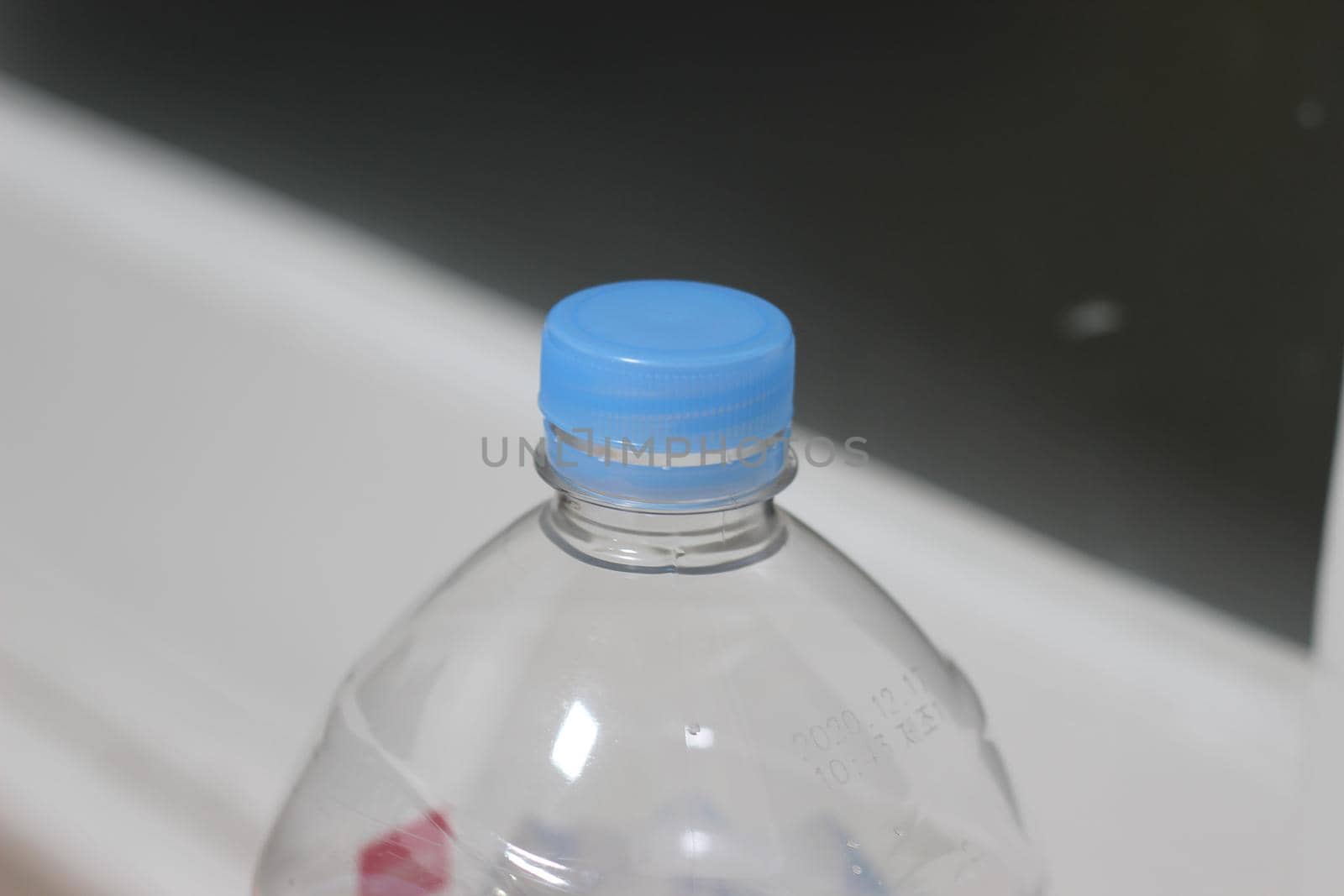 Selective focus of blue cap over plastic water bottle. Close-Up Of Bottle Over White Plastic Bottle