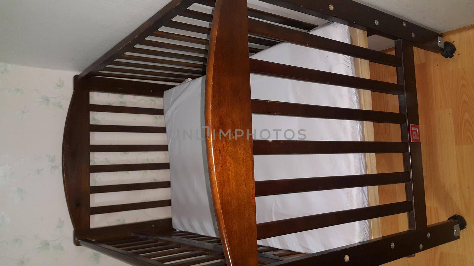 Crib by armchair at home on wooden floor