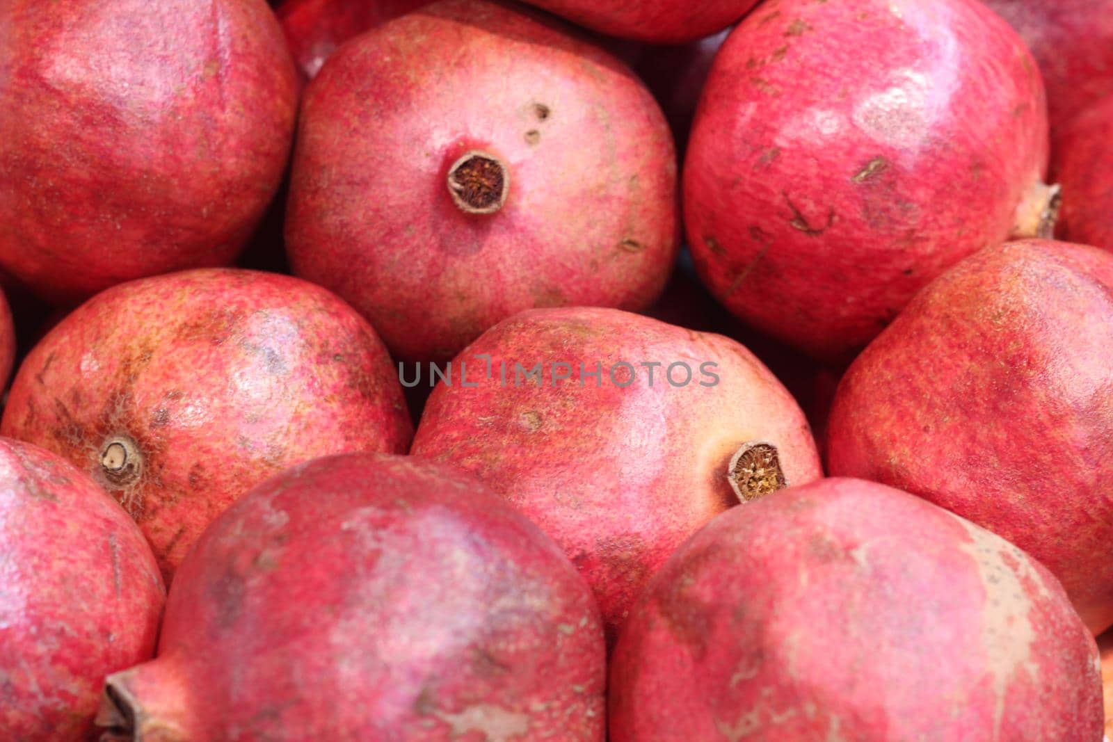 Fresh raw organic garnet fruit pile texture background. Red pomegranate fruits by Photochowk