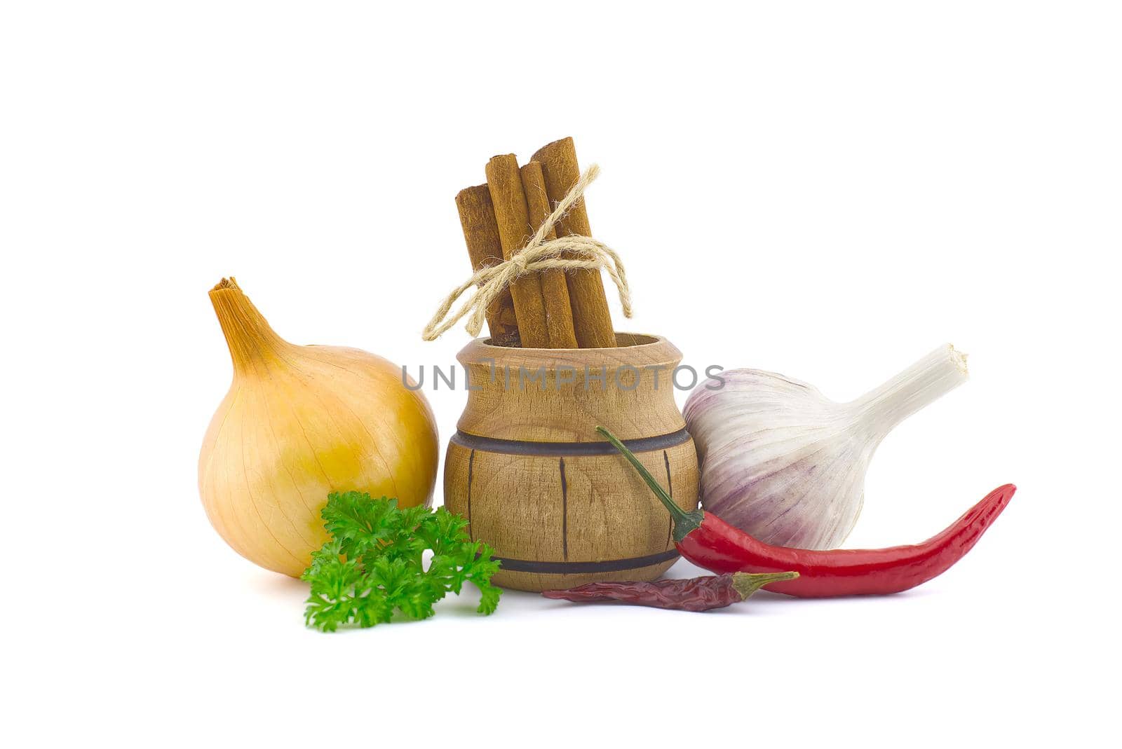 Garlic bulb, green parsley twig, golden-brown onion, cinnamon sticks bundle in a small wooden pot and fresh small red chili pepper isolated on white background