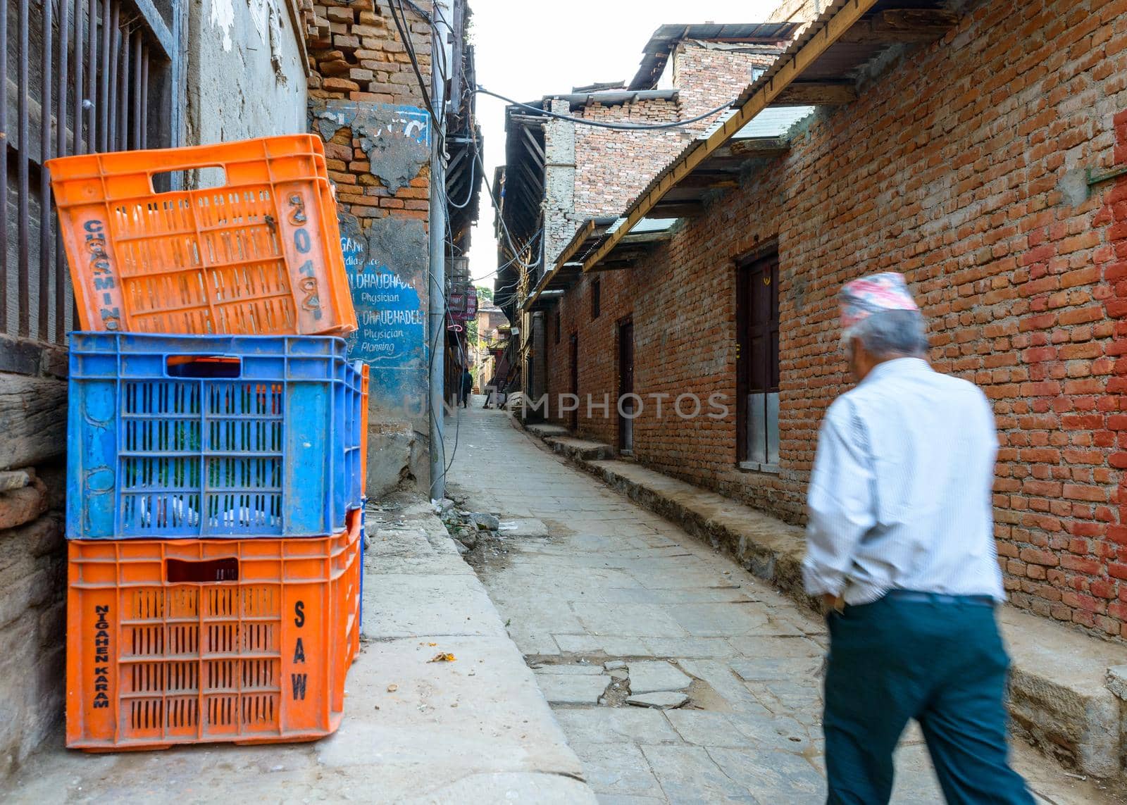 Nepalese man wearing a topi walks down a small alley. With motion blur. by dutourdumonde