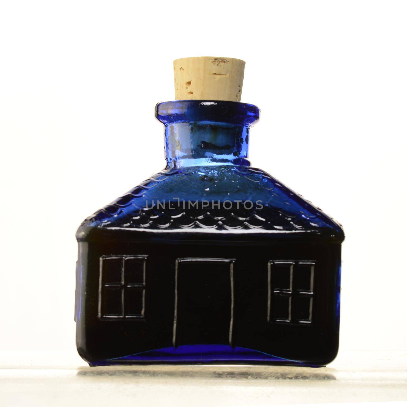 An isolated over white image of a blue glass school shape jar with a cork.