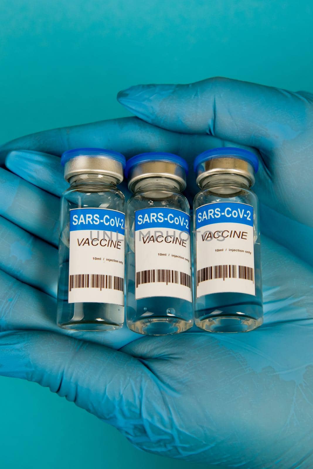 Female hands in blue gloves holding vials of the Covid-19 coronavirus vaccine. Close-up.