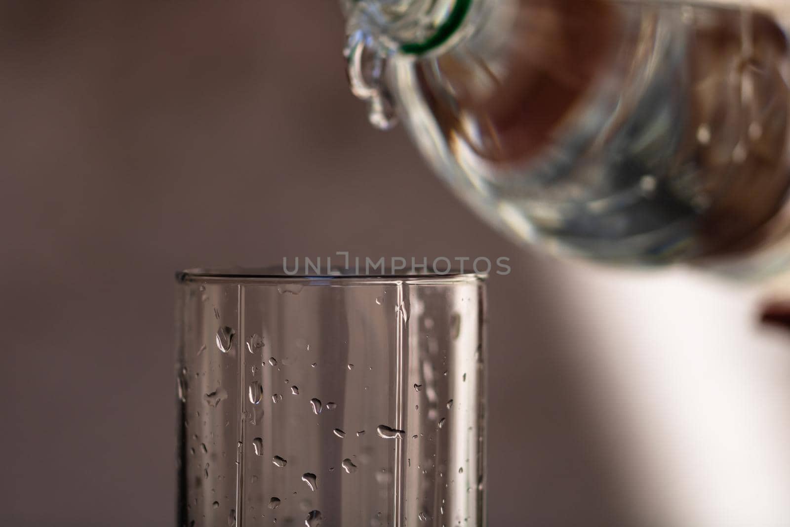 Pouring water from plastic bottle into a glass on blurred background. Selective focus and copy space