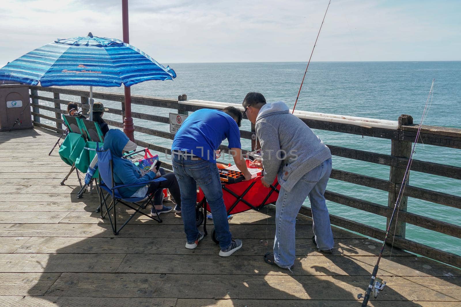 Tourist walking on the Oceanside Pier during blue summer day, Oceanside, northern San Diego County, California. Wooden pier on the western United States coastline. Famous for fisher. March 22nd, 2020