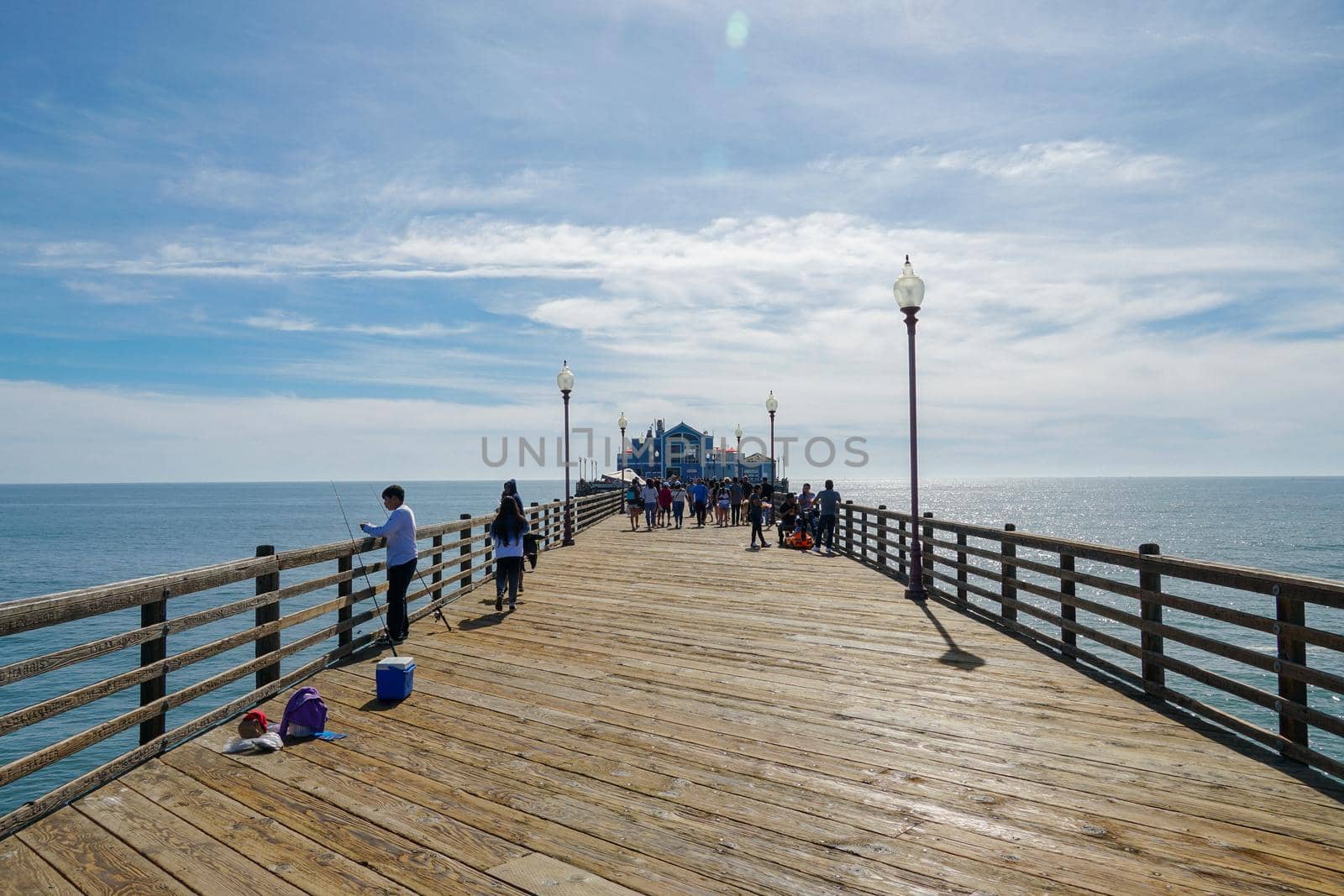 Tourist walking on the Oceanside Pier during blue summer day, Oceanside, northern San Diego County, California. Wooden pier on the western United States coastline. Famous for fisher. March 22nd, 2020