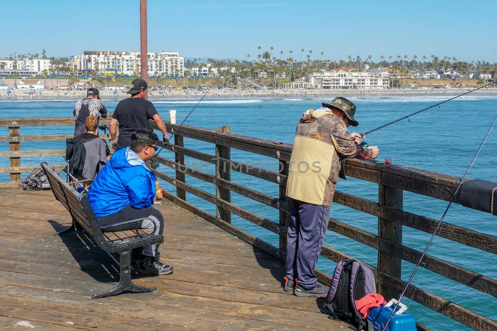 Tourist walking on the Oceanside Pier during blue summer day, Oceanside, northern San Diego County by Bonandbon