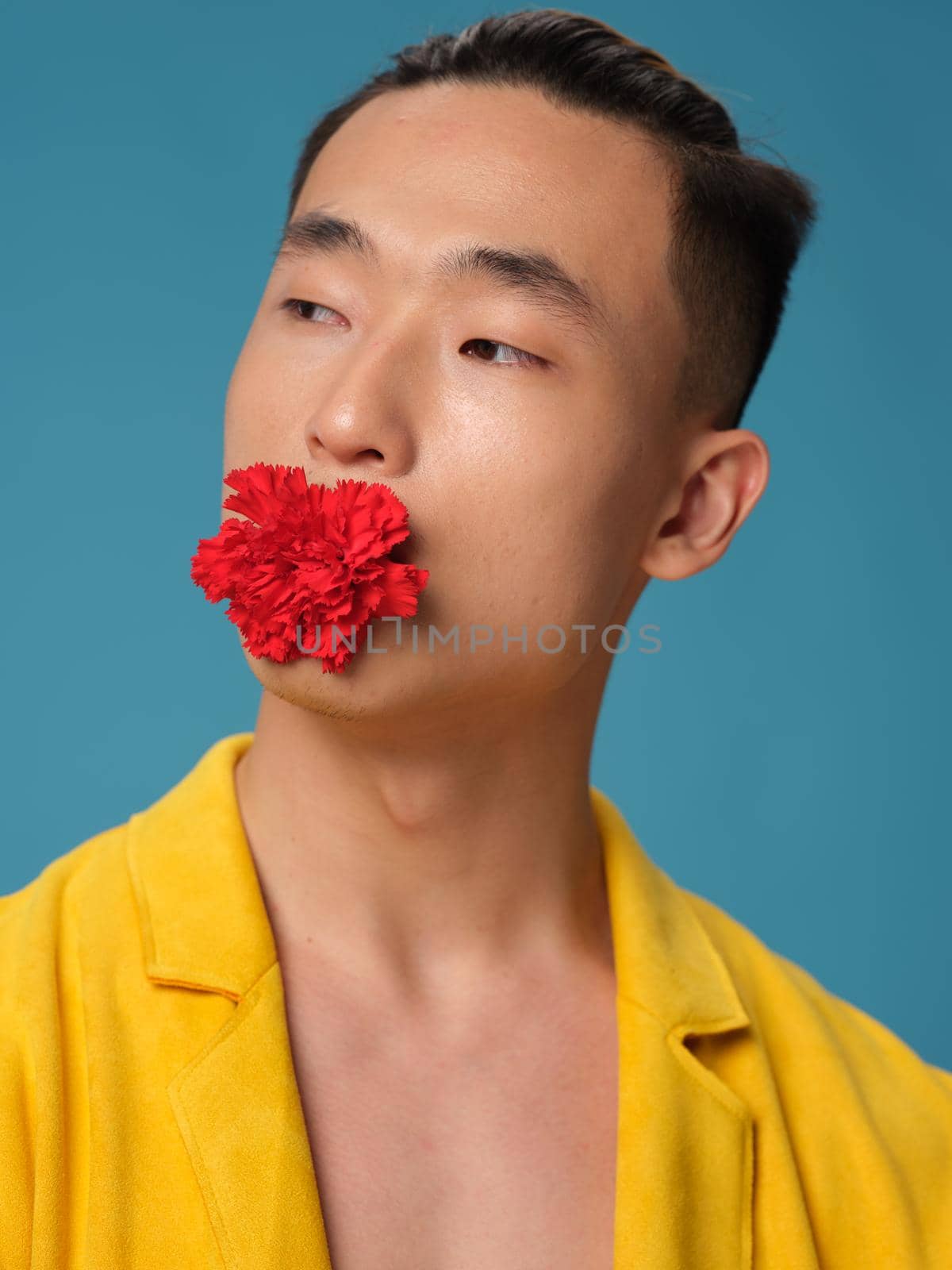 Portrait of a man with an Asian with a flower in his mouth on a blue background and a yellow jacket by SHOTPRIME