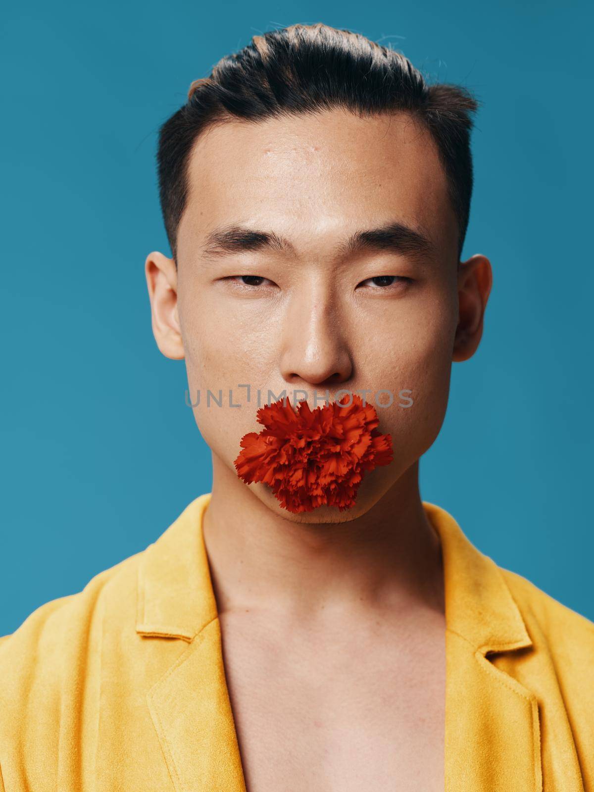 Portrait of a sexy man with a red flower in his mouth on a blue background by SHOTPRIME