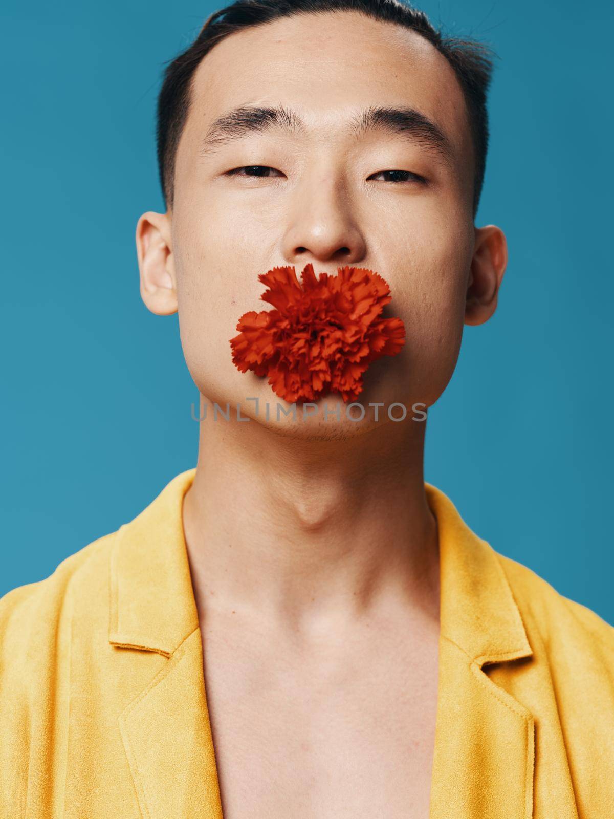 Sexy guy with a red flower in his mouth close-up portrait. High quality photo