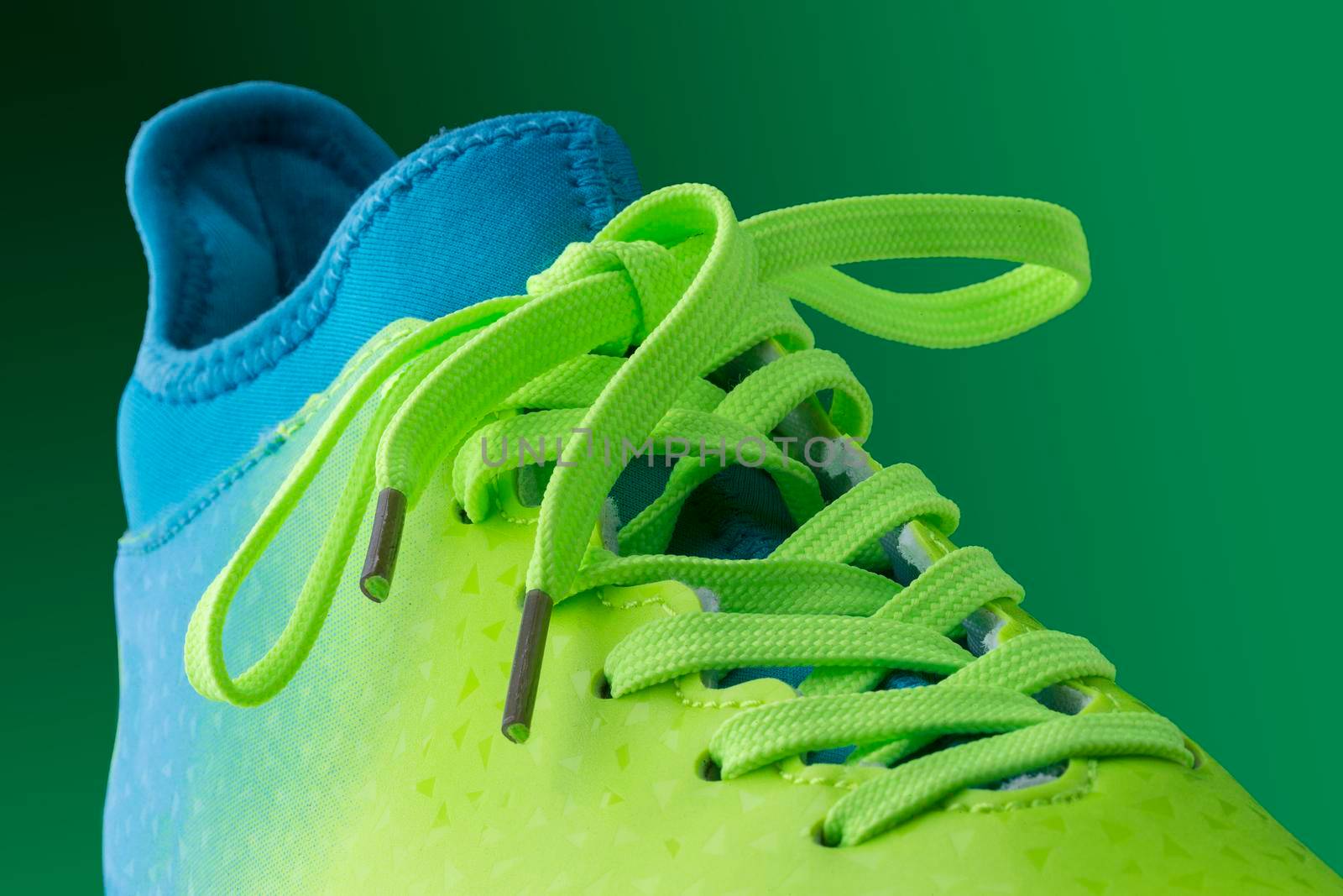 Green blue sneakers on a green background. Fragment of sports shoes close up. by Sviatlana