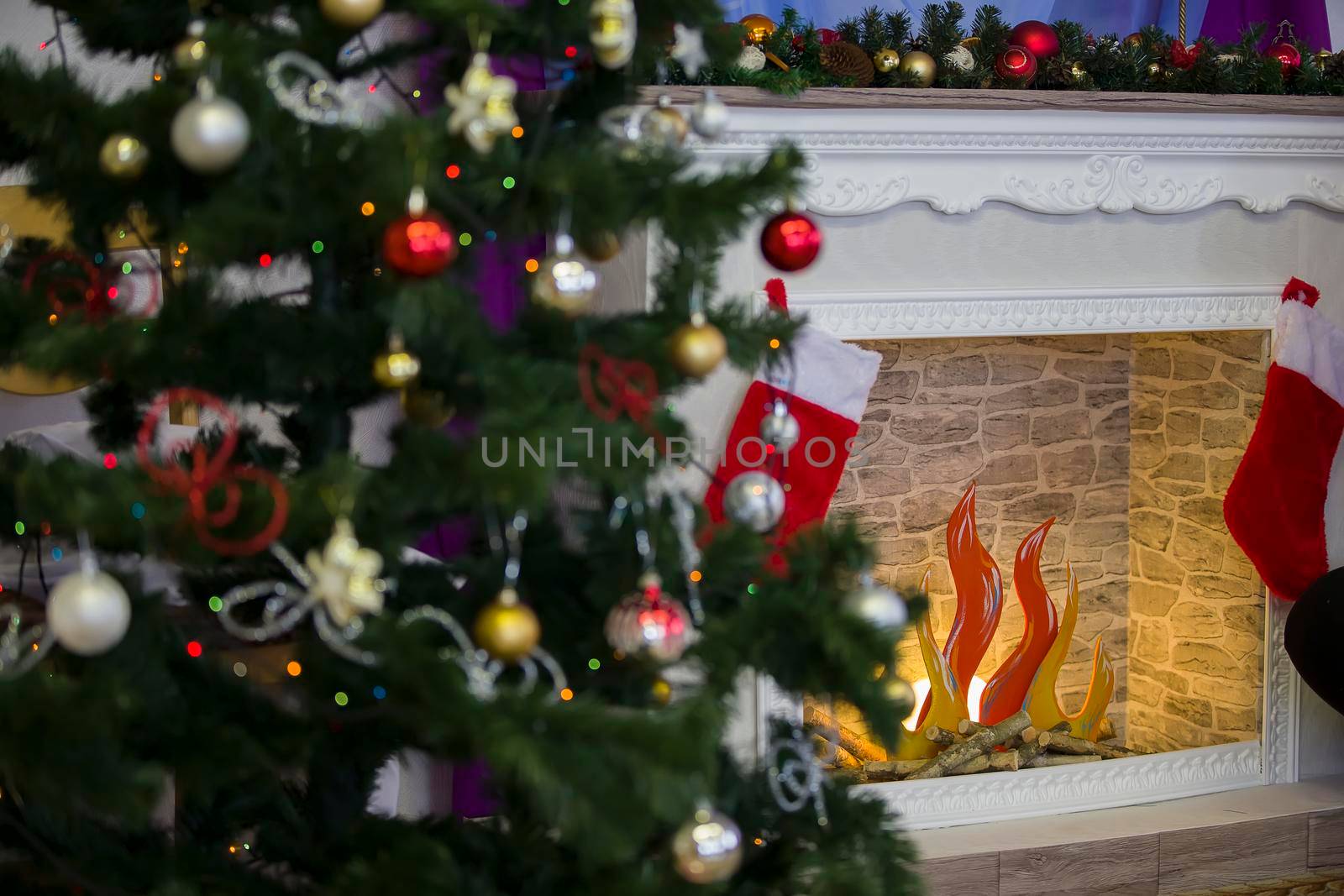 Fragment of a Christmas tree with toys on the background of an artificial fireplace.Christmas background