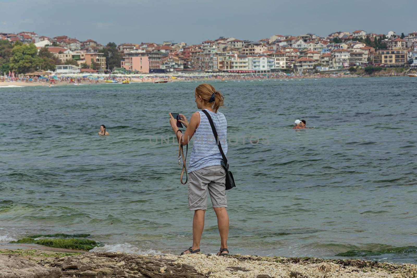 Bulgaria, Sozopol - 2018, 06 September: A woman on the beach with a smartphone, blurred background. Stock photo.