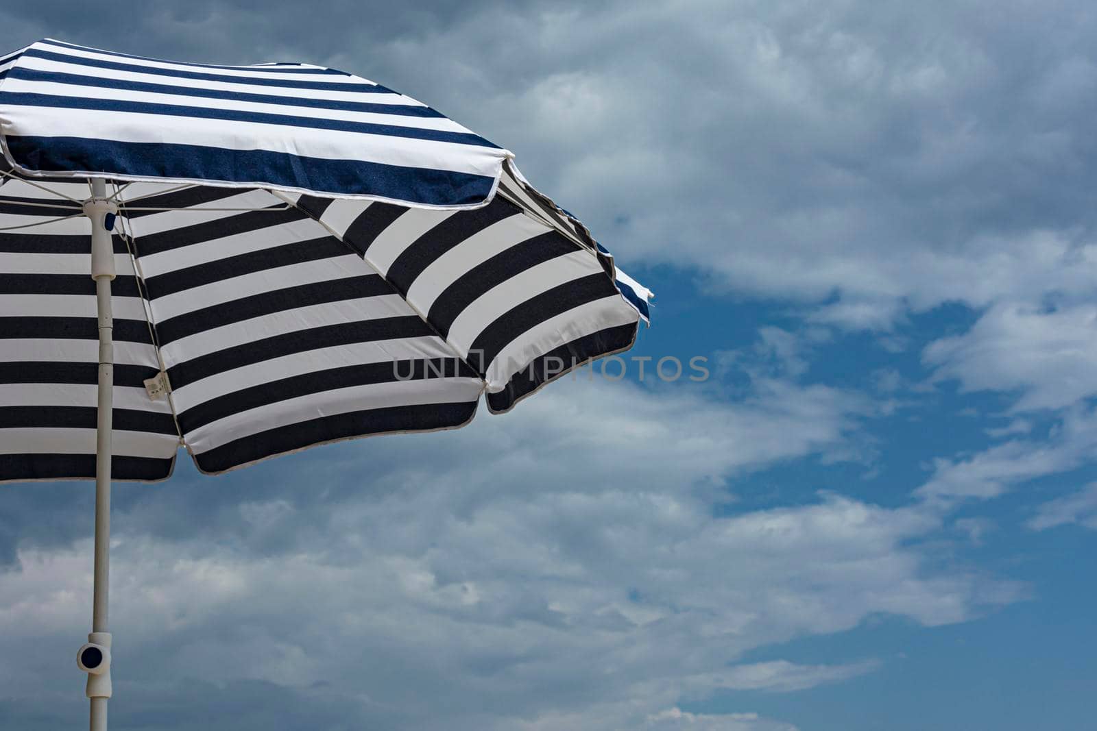 Beach umbrella from the sun on the background of blue sky with cirrus clouds. Stock photo.
