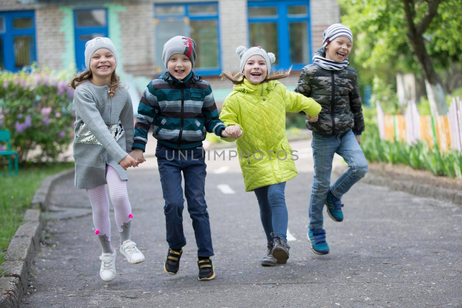 Belarus, the city of Gomel, May 10, 2019. Open day in kindergarten.Happy preschoolers on the street. Children holding hands jumping. A group of six year old friends.