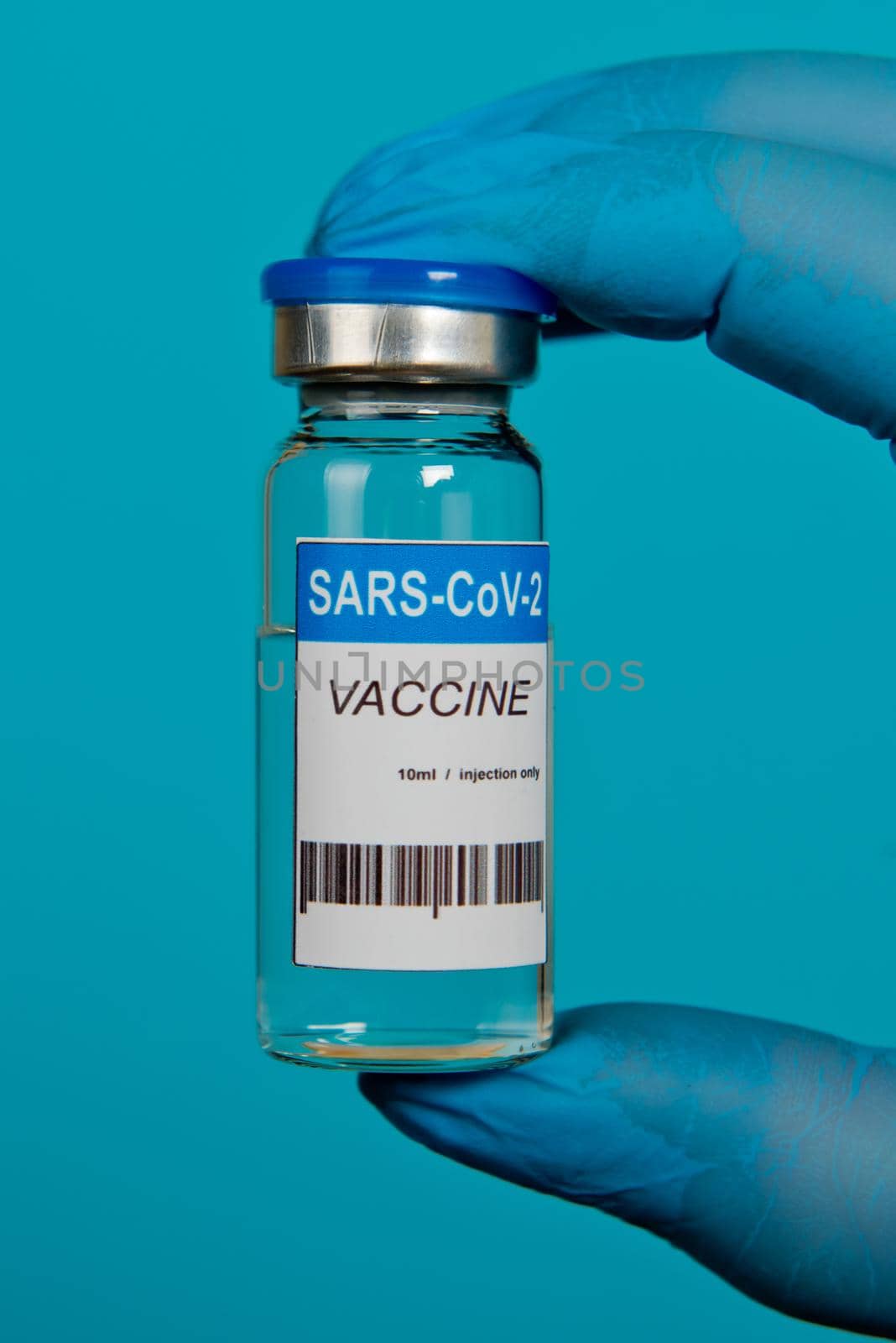 Hands in blue gloves holding vial of the Covid-19 coronavirus vaccine. Close-up.