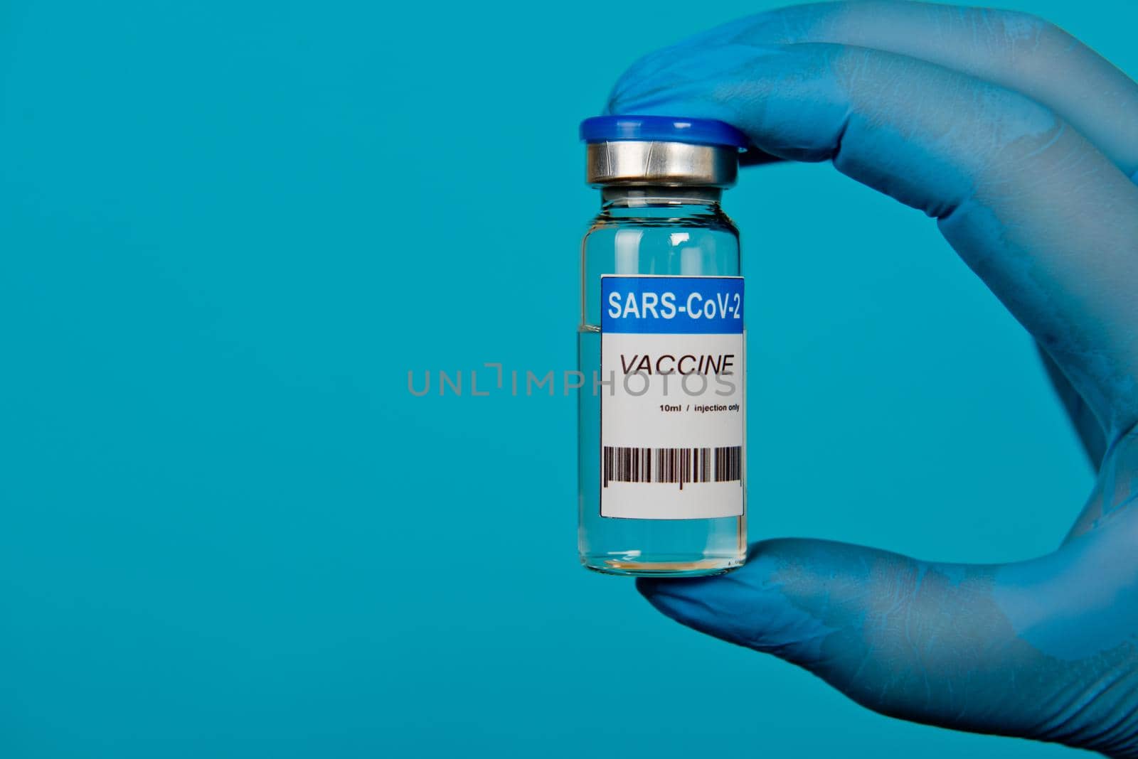 Hands in blue gloves holding vial of the Covid-19 coronavirus vaccine. Close-up.