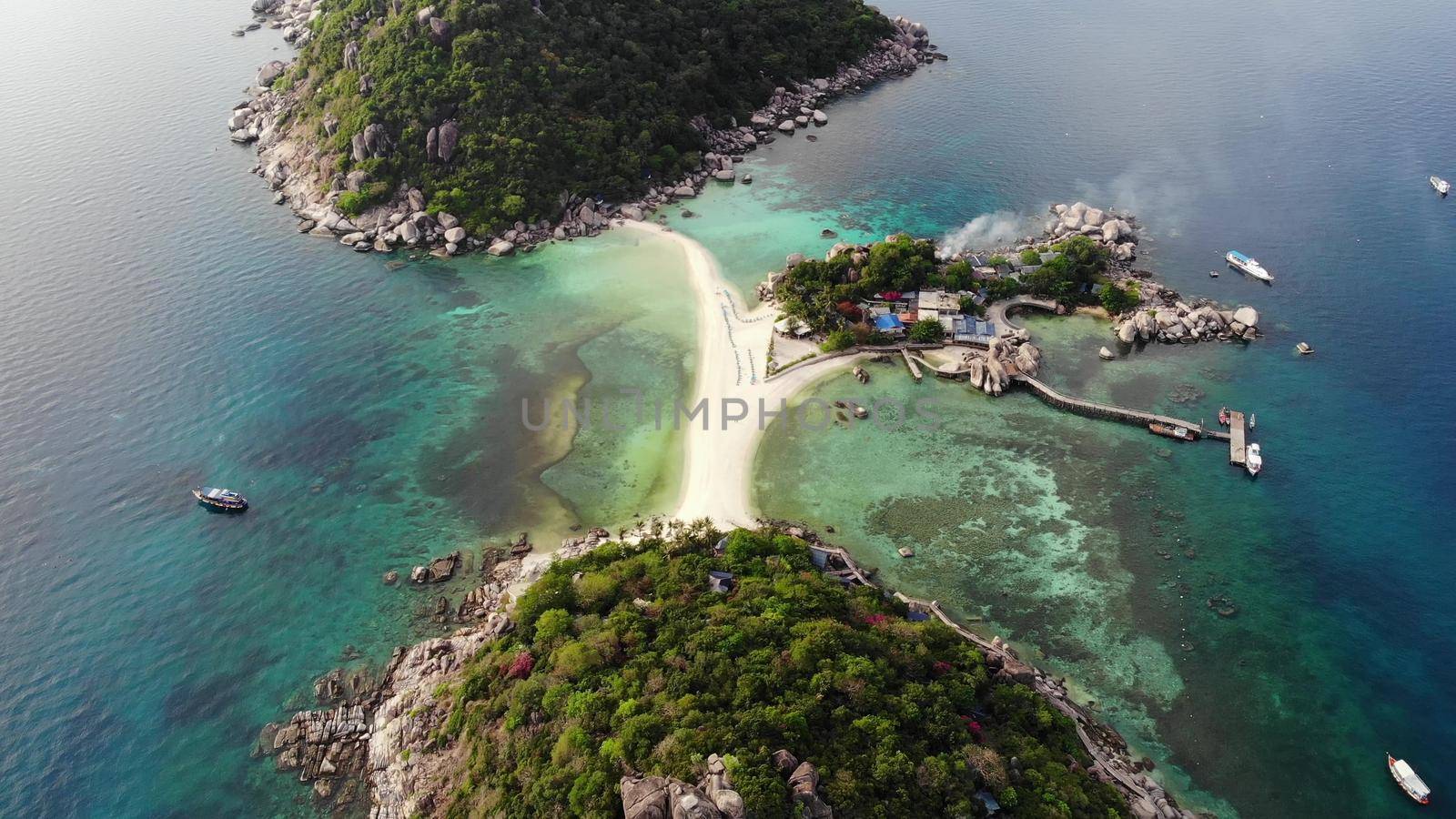 Calm colorful azure turquoise sea near tiny tropical volcanic island Koh Tao, unique small paradise Nang Yuan. Drone view of peaceful water near stony shore and green jungle on sunny day in Thailand