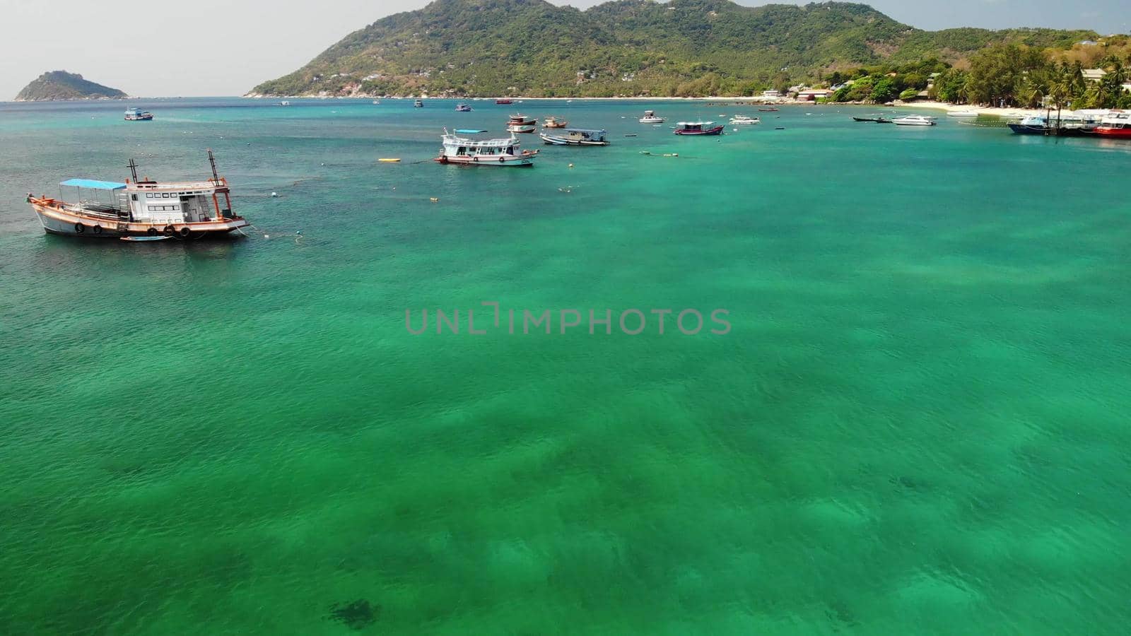 Boats in calm sea in port. Drone view of fishing and dive boats floating on tranquil surface of blue sea in harbor of tropical exotic paradise Koh Tao Island on sunny day in Thailand by DogoraSun