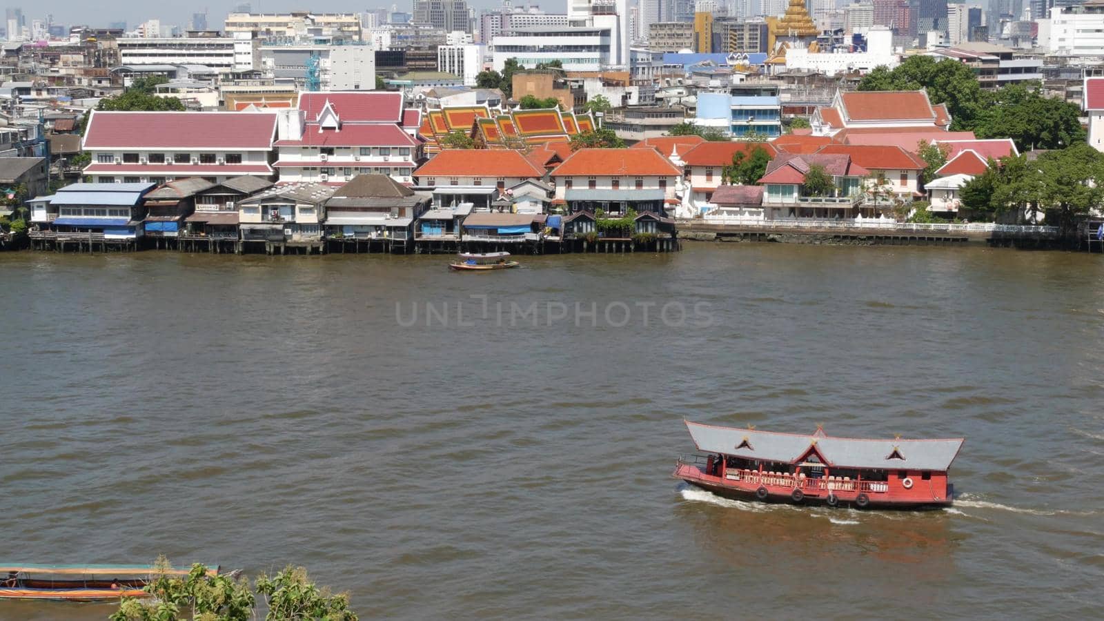 Oriental boat floating on river in Krungthep city. Modern transport vessel floating on calm Chao Praya river on sunny day in Bangkok near chinatown. Panorama.