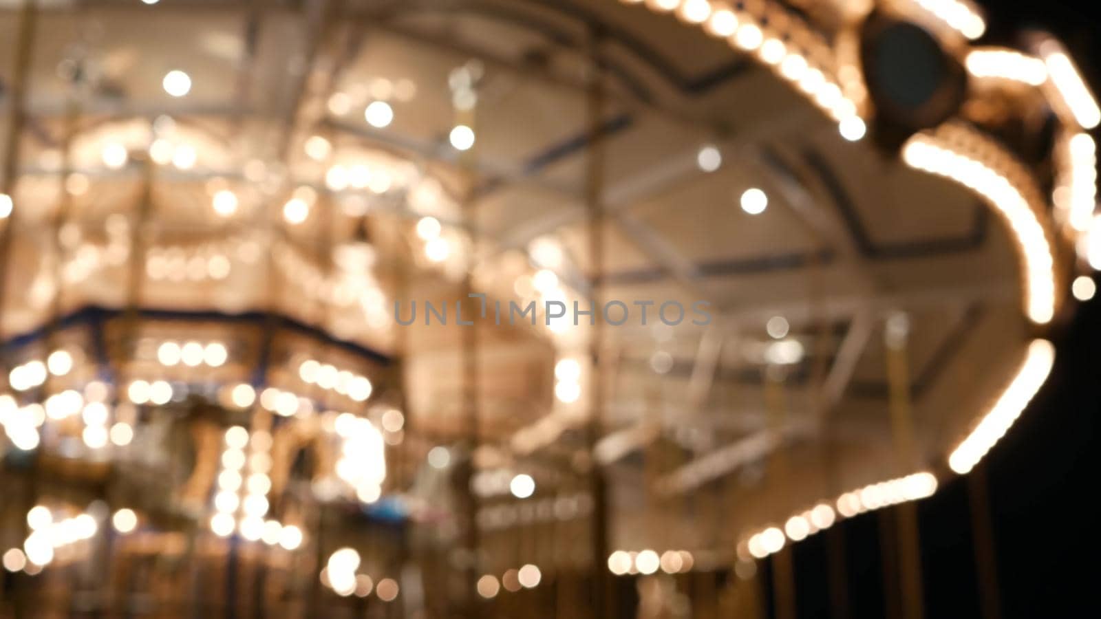 Illuminated blurred merry go round in park. Brightly illuminated roundabout spinning in wonderful amusement park at night.