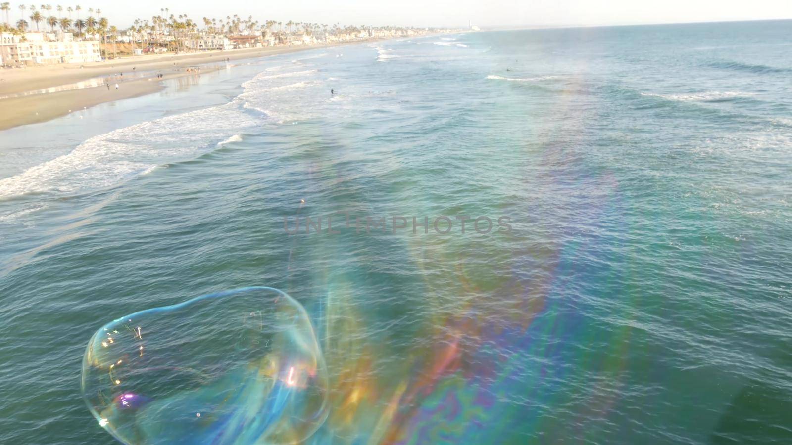 Blowing soap bubbles on ocean pier in California, blurred summertime background. Creative romantic metaphor, concept of dreaming happiness and magic. Abstract symbol of childhood, fantasy, freedom by DogoraSun