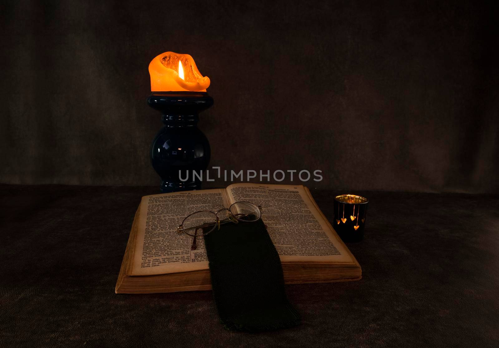 Burning candle and an open old Christian book still life