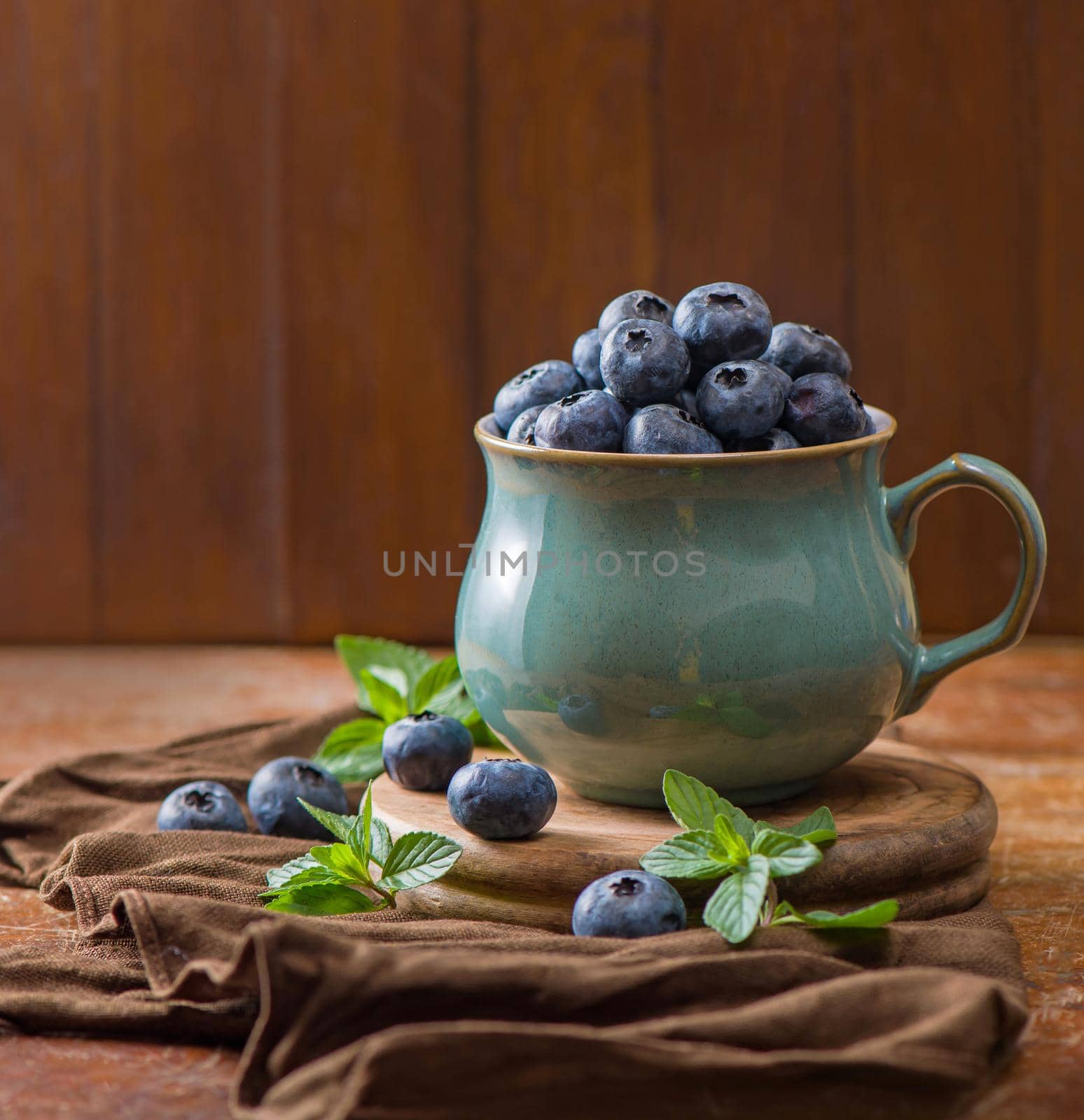 Fresh blueberry in a cup with leaves of mint.