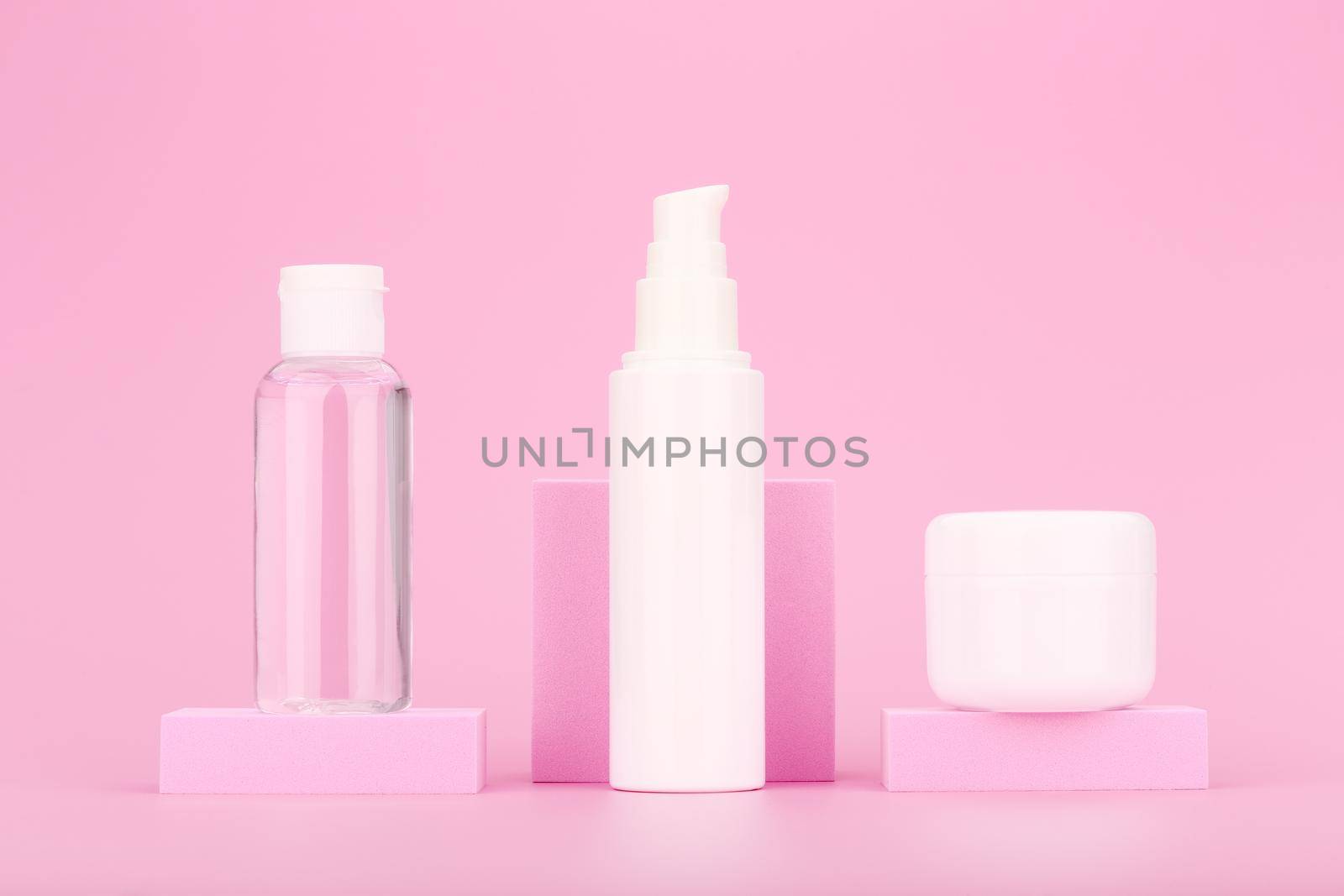 Set of cosmetic bottles on pink podium against pink background. Concept of beauty products and daily skin routine by Senorina_Irina