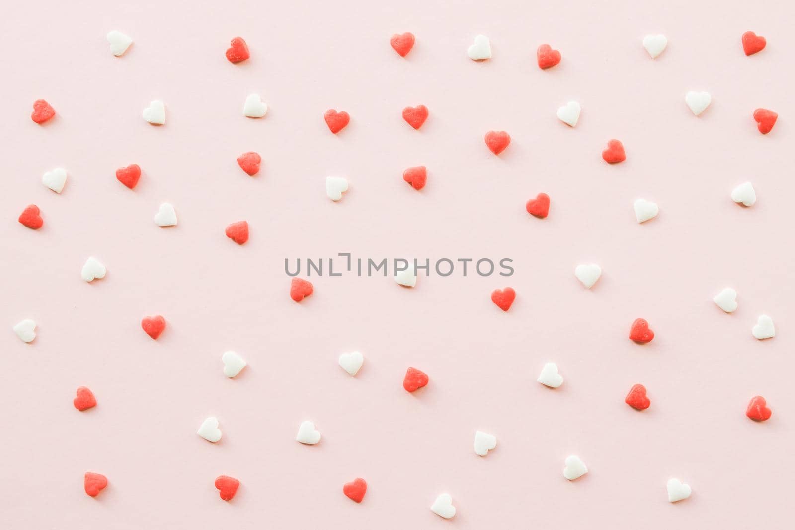 Valentine's Day background with red and white little hearts on pink backdrop. Valentines day concept. Copy space. Top view