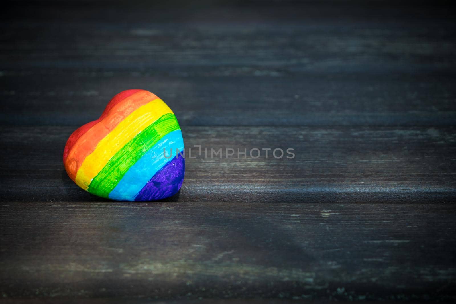 Heart with rainbow stripes on dark wooden background. LGBT pride flag, symbol of lesbian, gay, bisexual, transgender for social movements. Homosexual love,Equality or Human rights concept. Copy space.