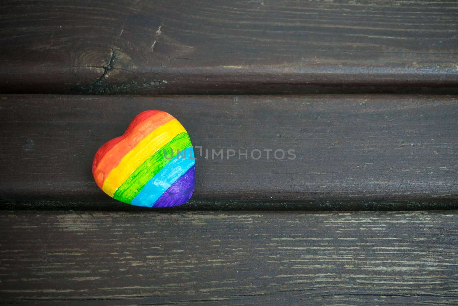 Heart with rainbow stripes on dark wooden background. LGBT pride flag, symbol of lesbian, gay, bisexual, transgender for social movements. Homosexual love,Equality or Human rights concept. Copy space.