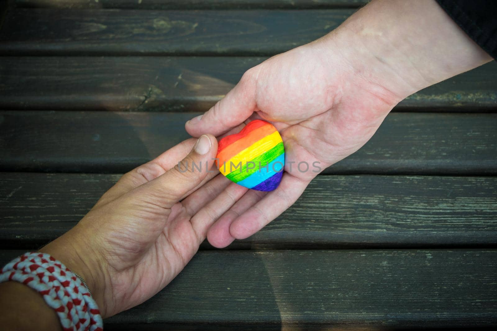 Heart with rainbow stripes in male hands. LGBT pride flag, symbol of lesbian, gay, bisexual, transgender for social movements. Homosexual love,Equality or Human rights concept. Copy space.
